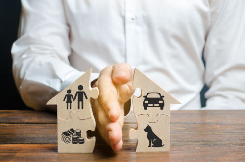 A man splits a house with his palm with images of property, children and pets. - KM Family Law